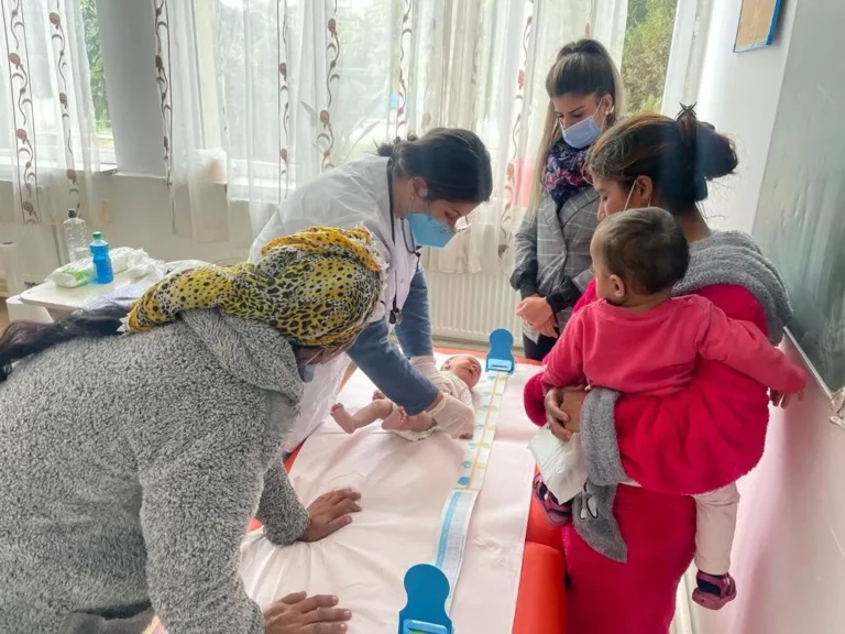 Medic pediatru consultând un bebeluș în caravana medicală