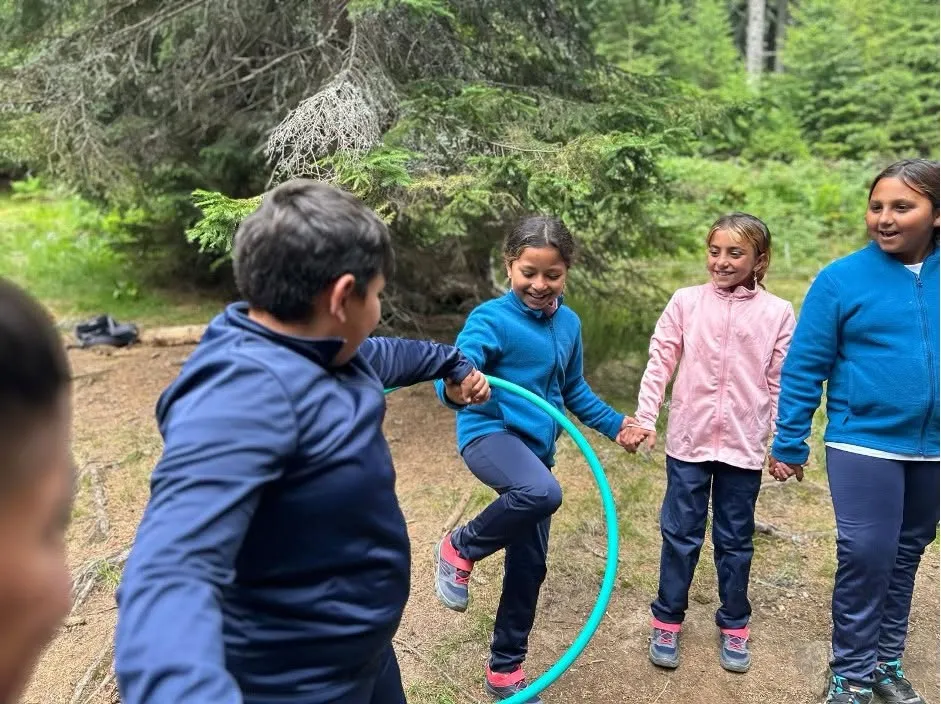 Copii jucându-se cu cercul de hula-hoop în pădure